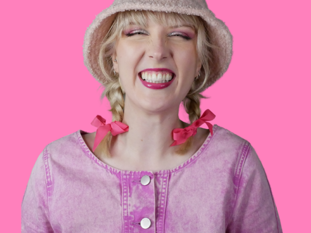 A portrait of Rosie Russel in a pink outfit with a huge smile