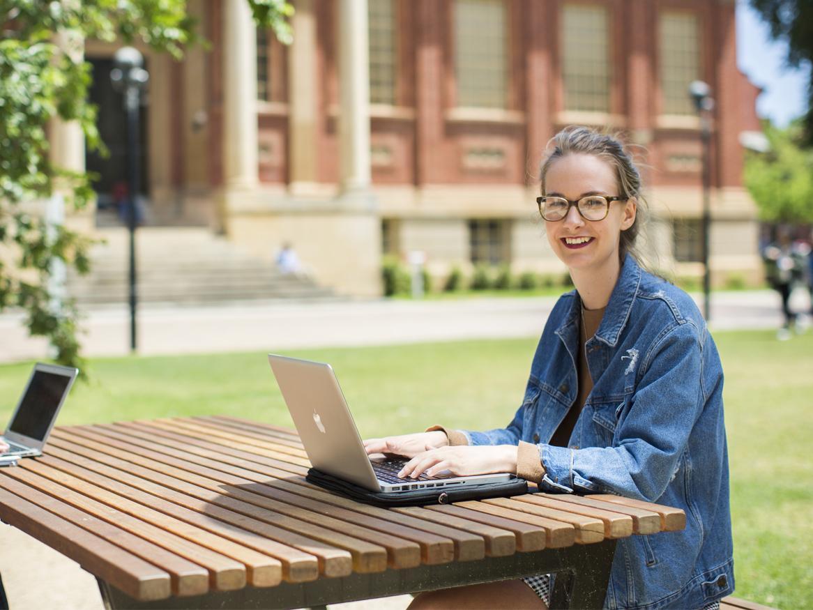 student with laptop in front of Barr Smith Library