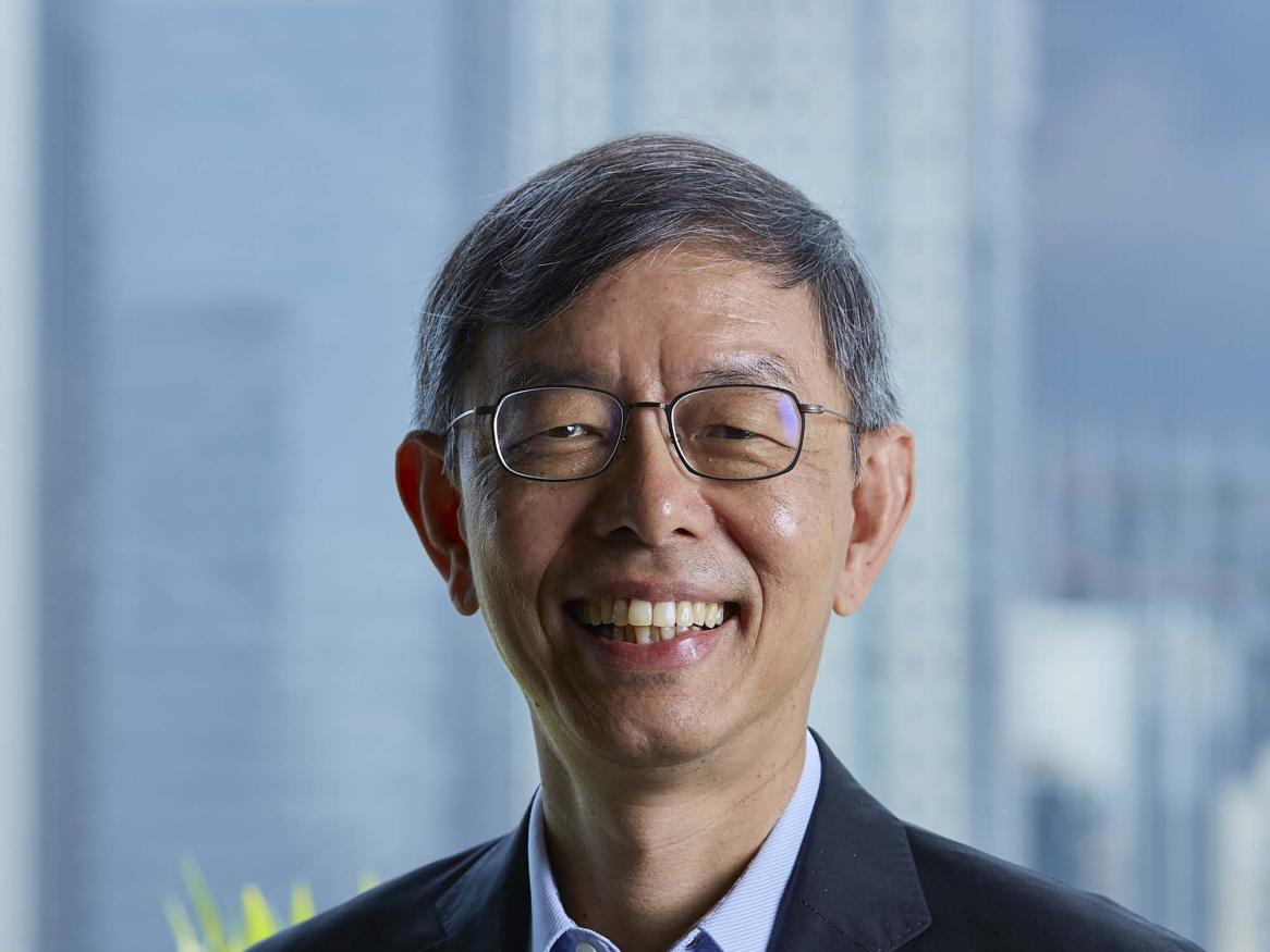A portrait of Peter Ong smiling, wearing a suit