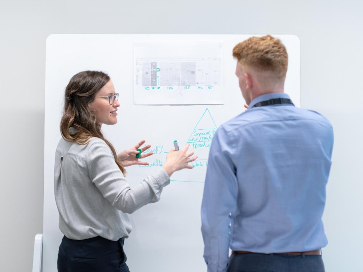 Two engineers examine data on a whiteboard