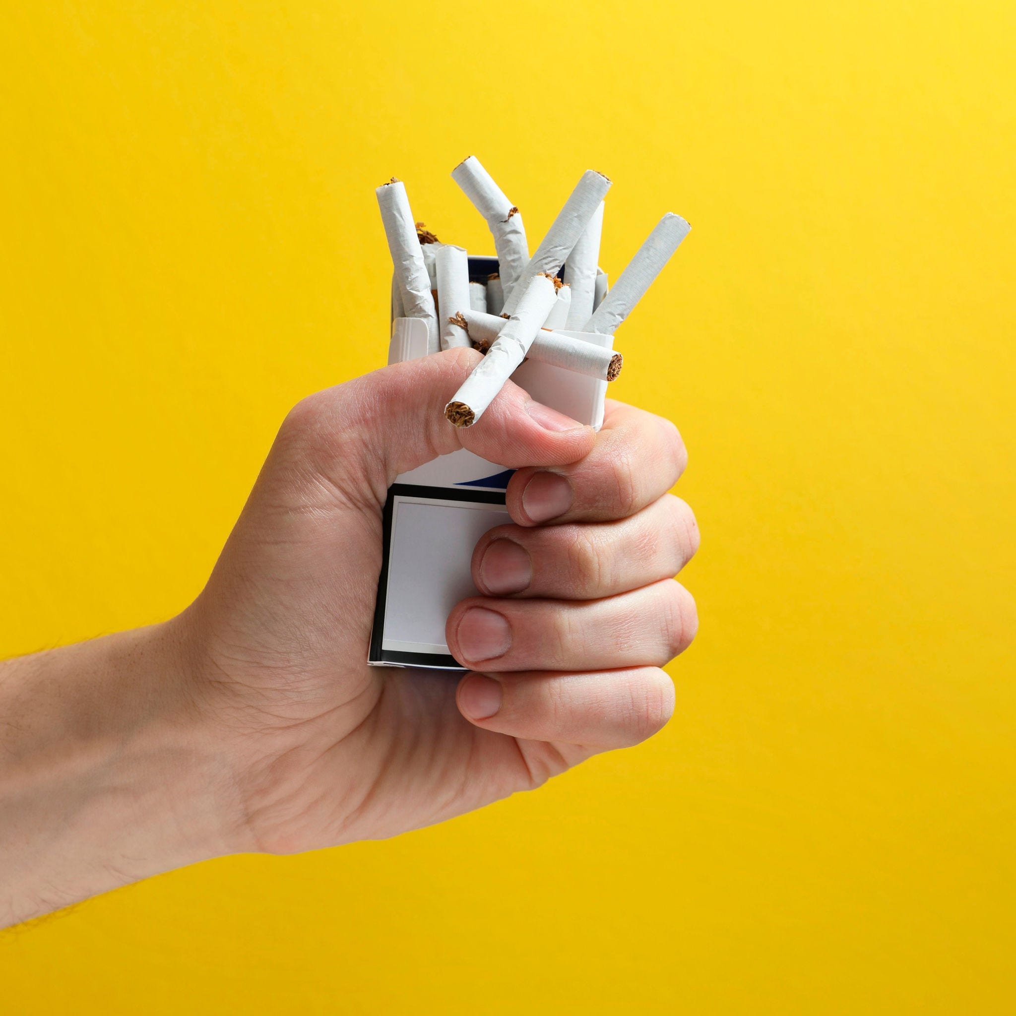 Pack of cigarettes being crushed in hand grip
