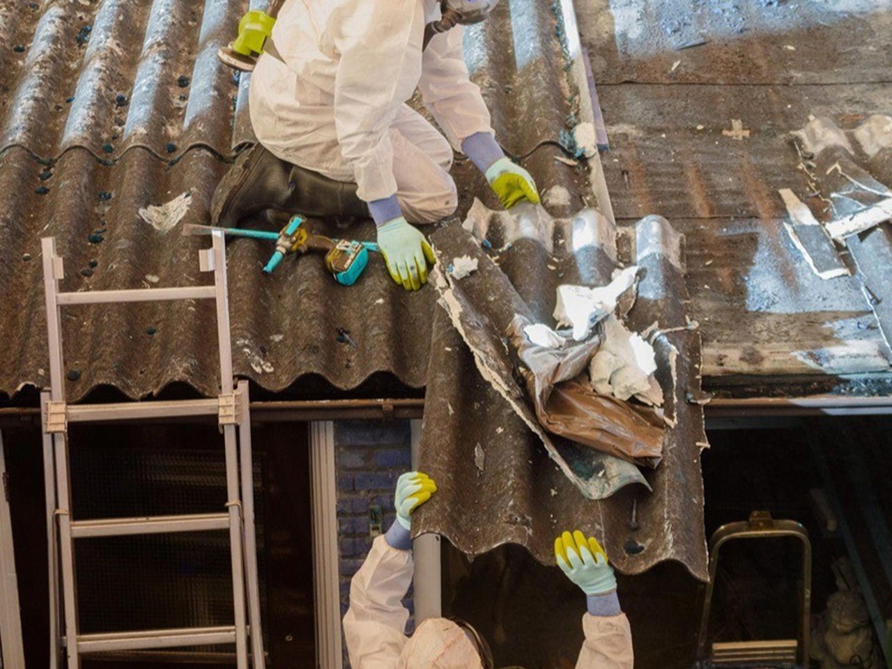 Professionals remove asbestos roofing from a home.