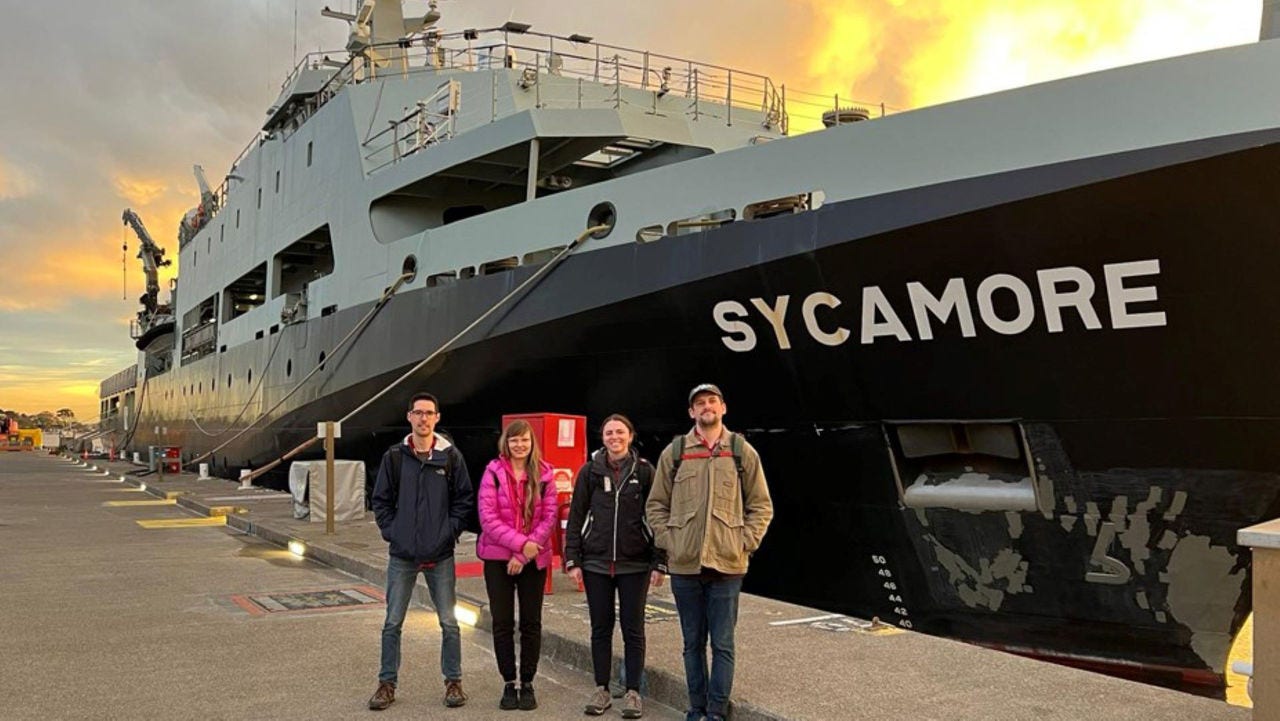 People standing in front of a navy ship