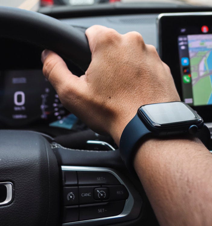 an arm with a smartwatch on a steering wheel