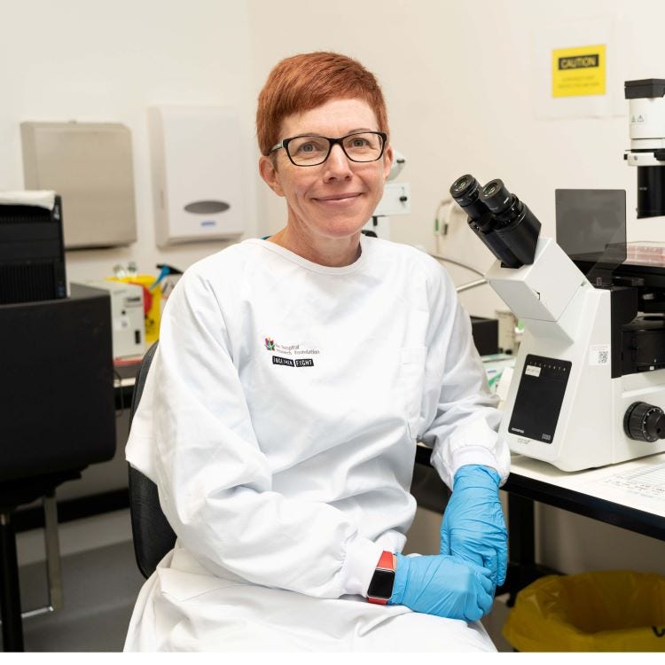Photo of Associate Professor Susan Woods sitting near a microscope