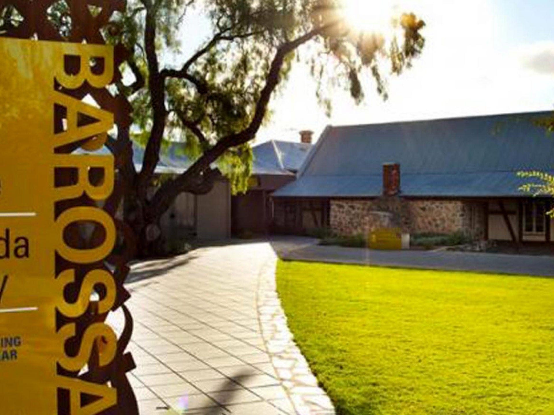 Barossa Valley sign with a gumtree, stone building, grass and the sun in the background