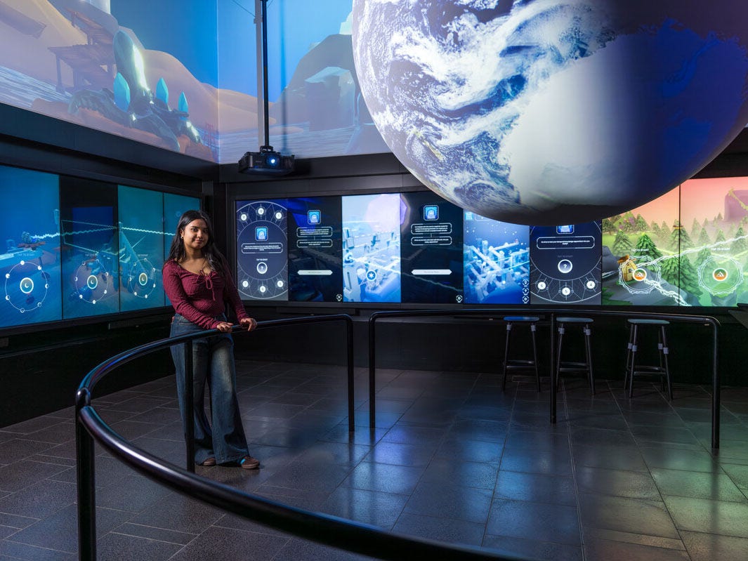 A museum exhibit with a large, glowing globe and screens showing planetary data