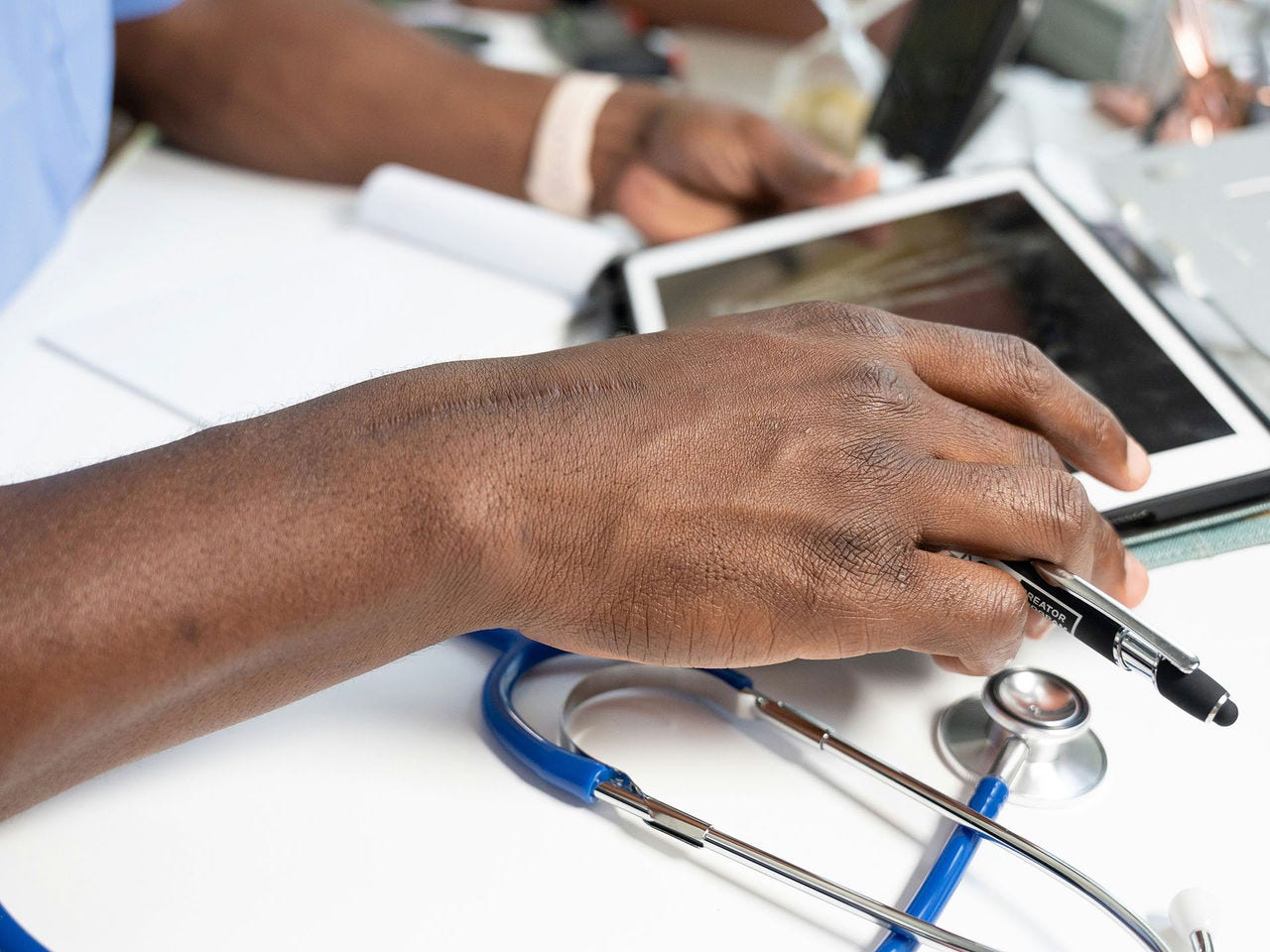 A health professional's hand holding and viewing medical data on a tablet