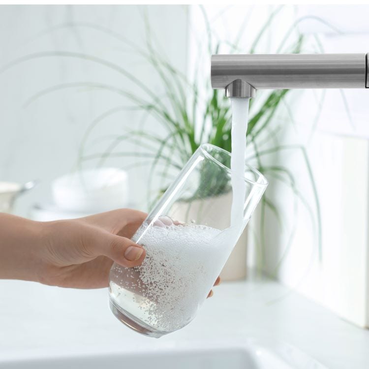 Photo of woman filling up a glass of water from the tap.