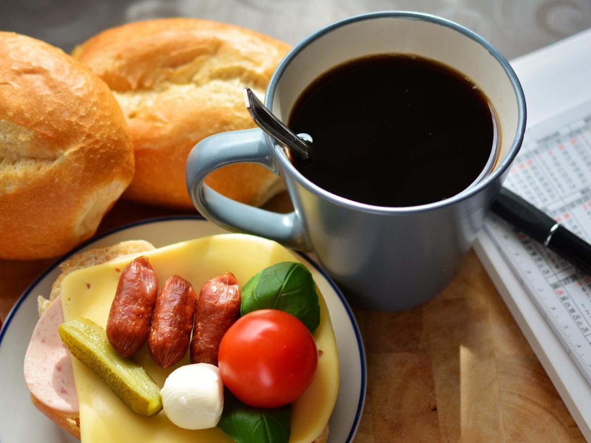 coffee cup, continental breakfast and diary with pen on a table