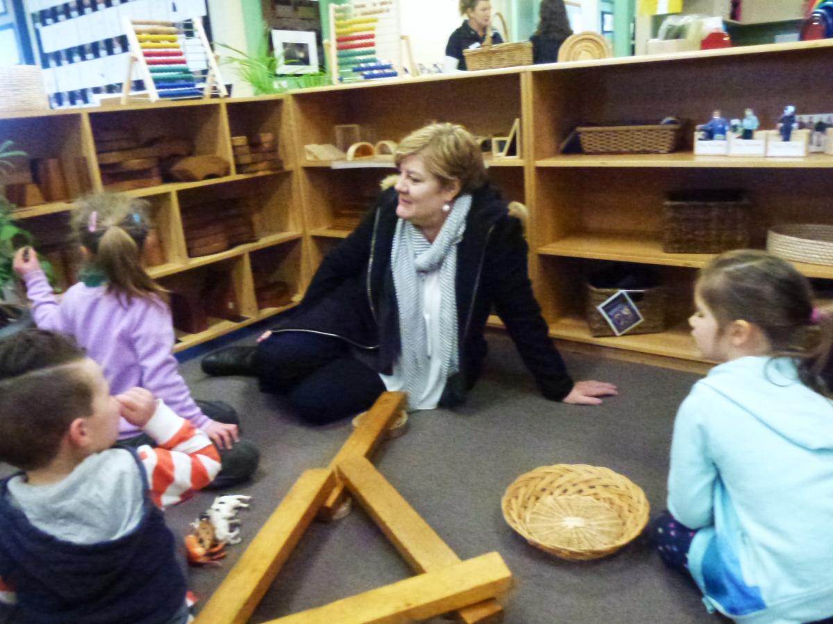 Helen Connolly sits on the floor with three children at a kindergarten