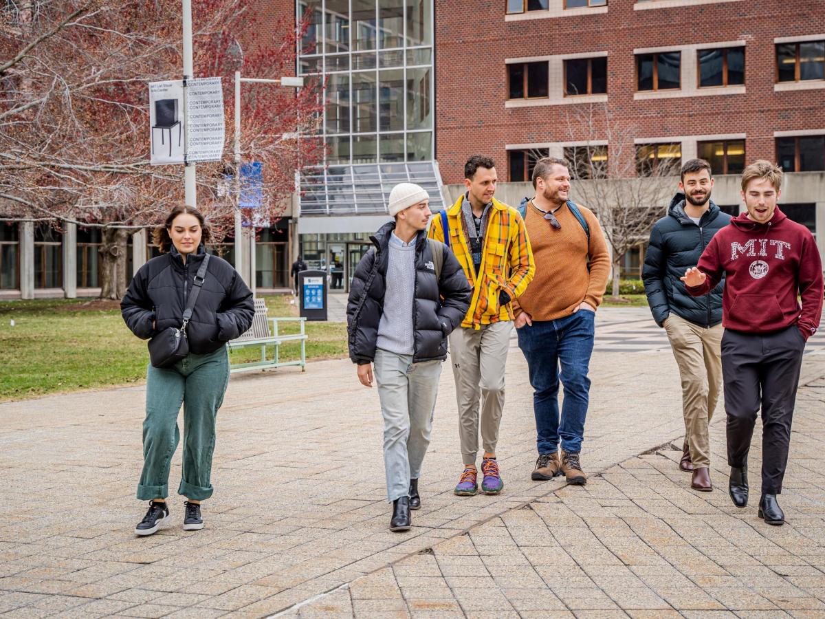 Tobin walks across campus with friends, wearing an MIT hoodie