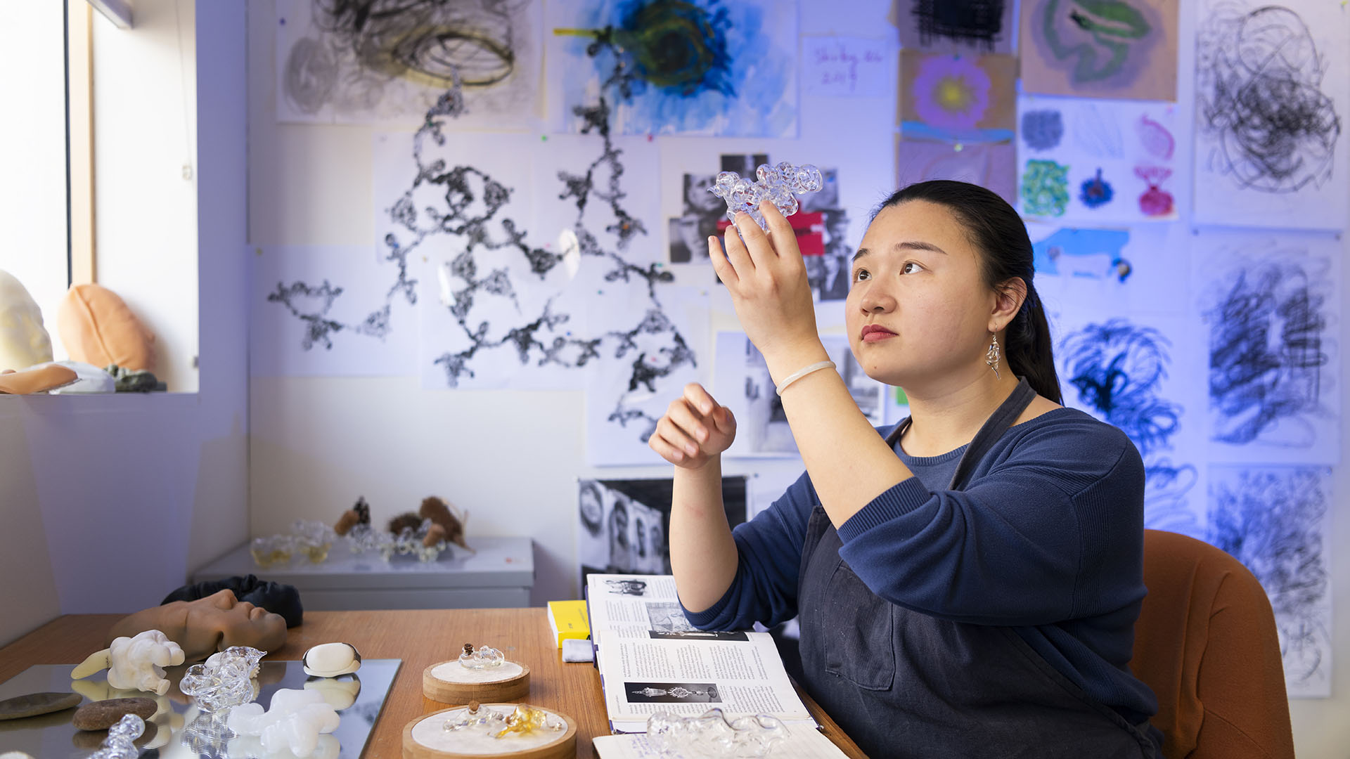 Student creating a design with glass