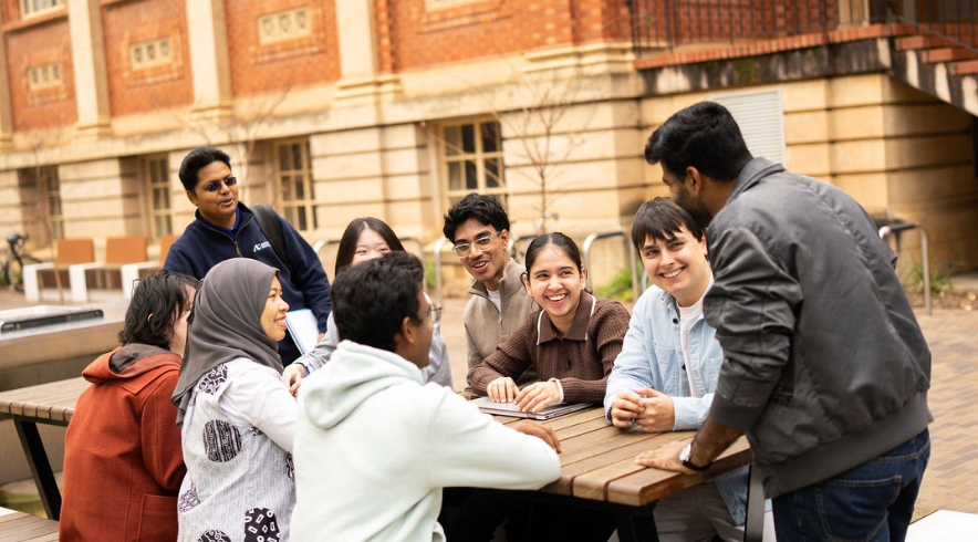 AU students sitting around an outdoor bench - City East Campus 