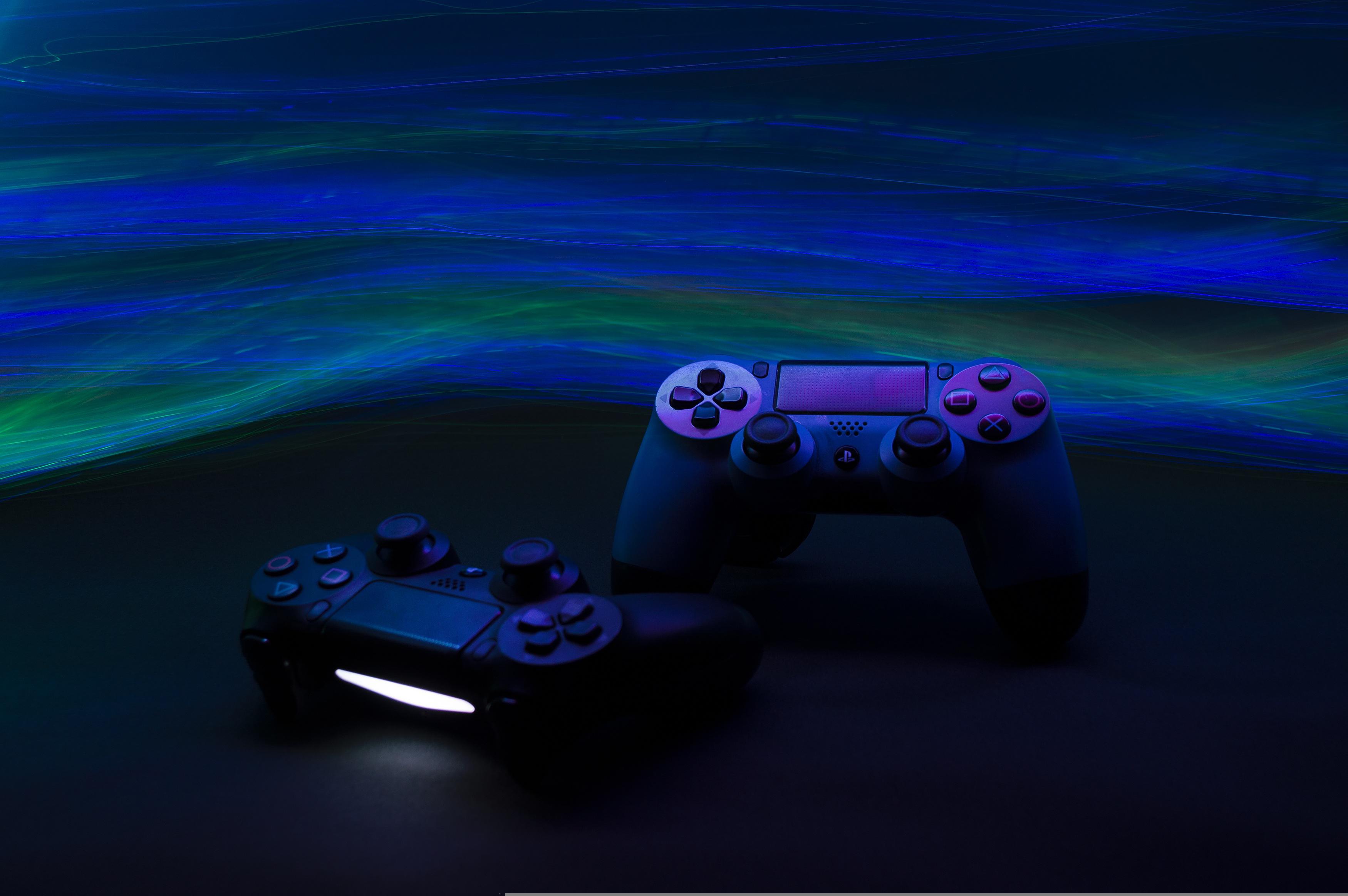 Gaming console controllers with a dark blue and green wavy background