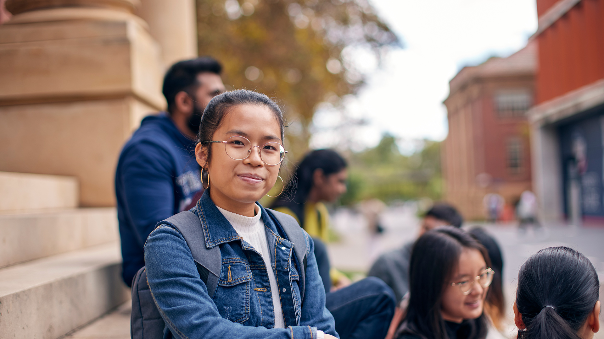 Student sitting on the step of a building on campus