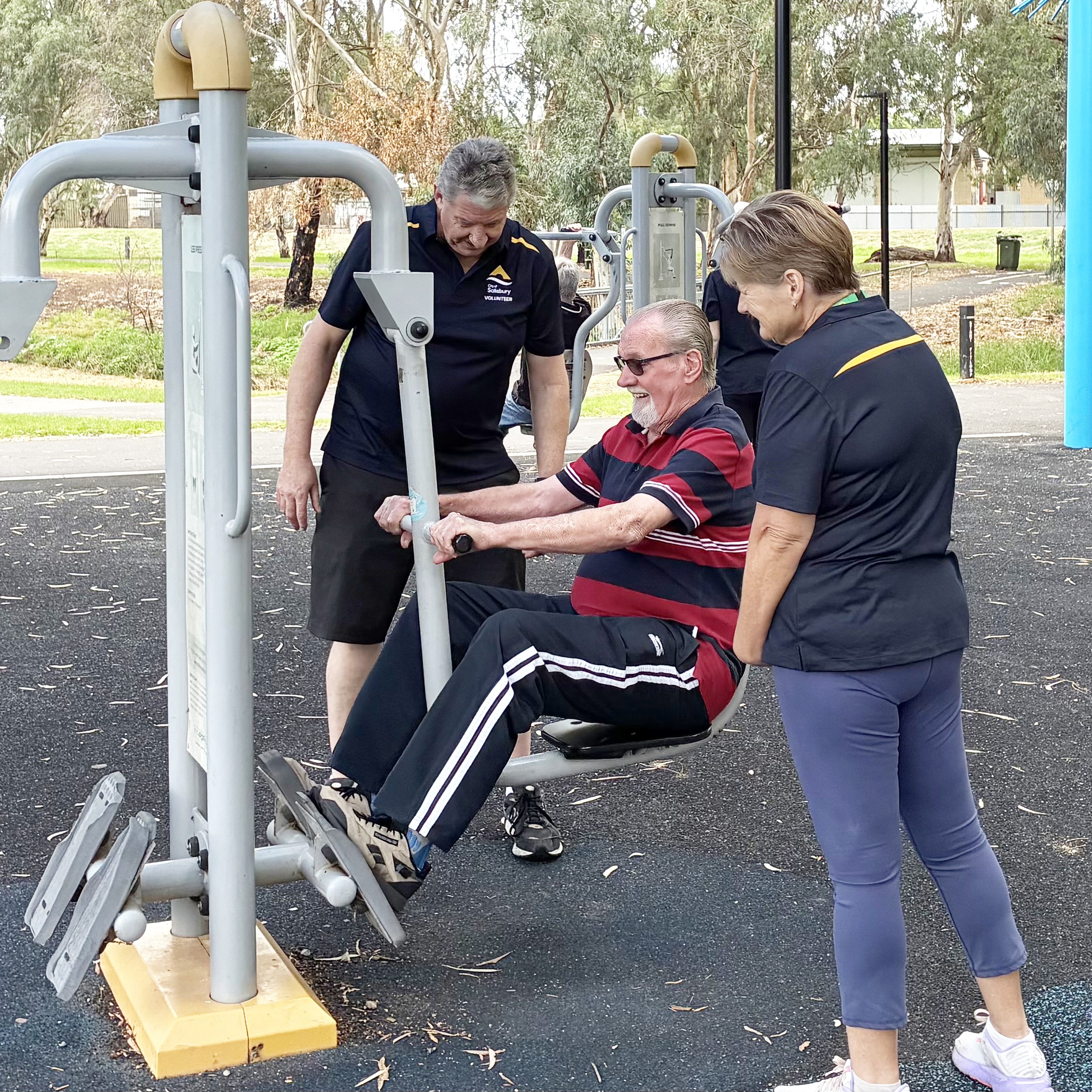 Older man working out on gym equipment with peer leader