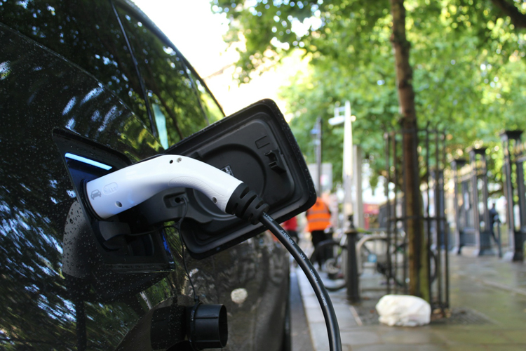 An electric vehicle charges on a street.