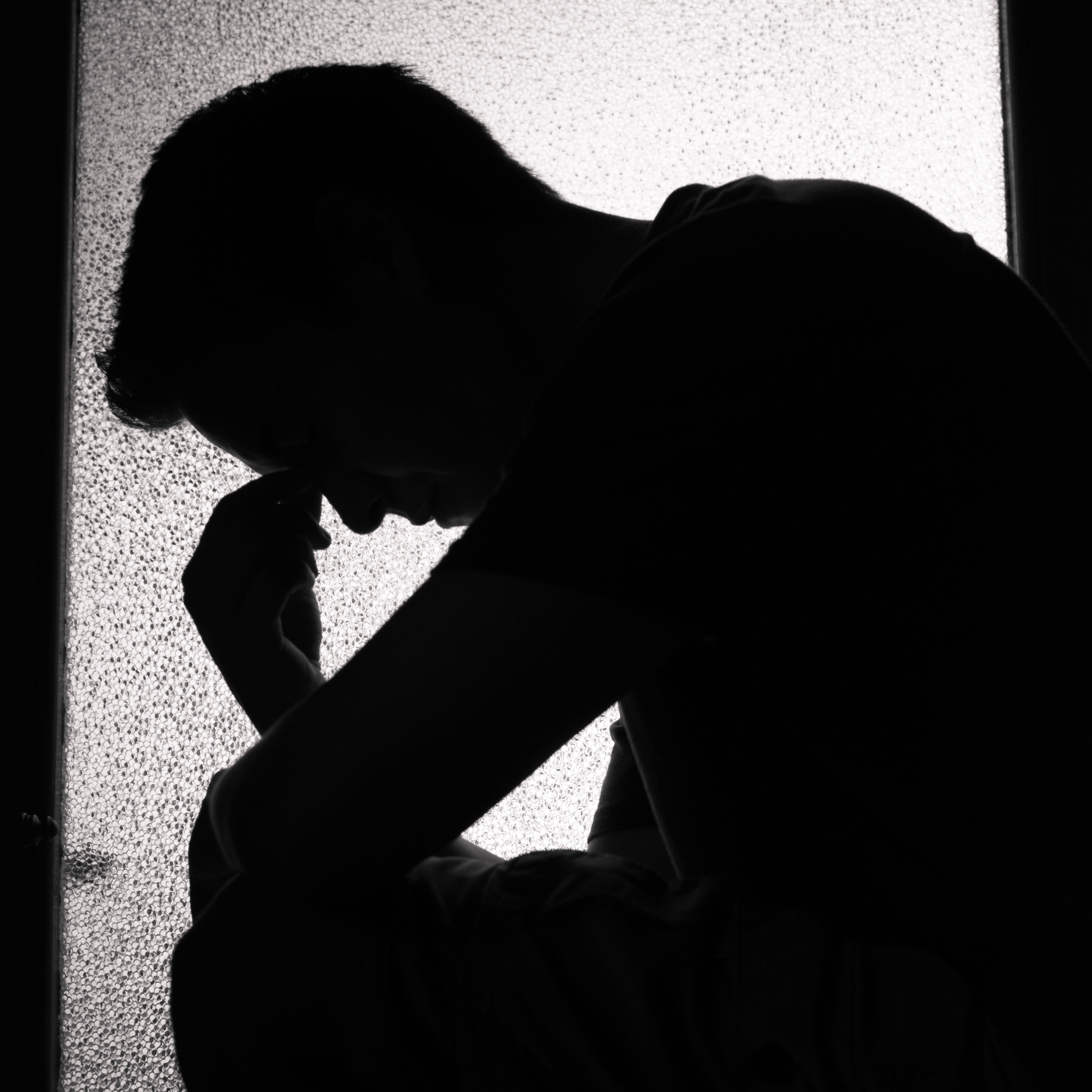 siloutette of man holding his head in despair
