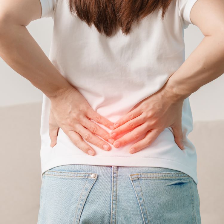 Stock image of a woman with hands on lower back.