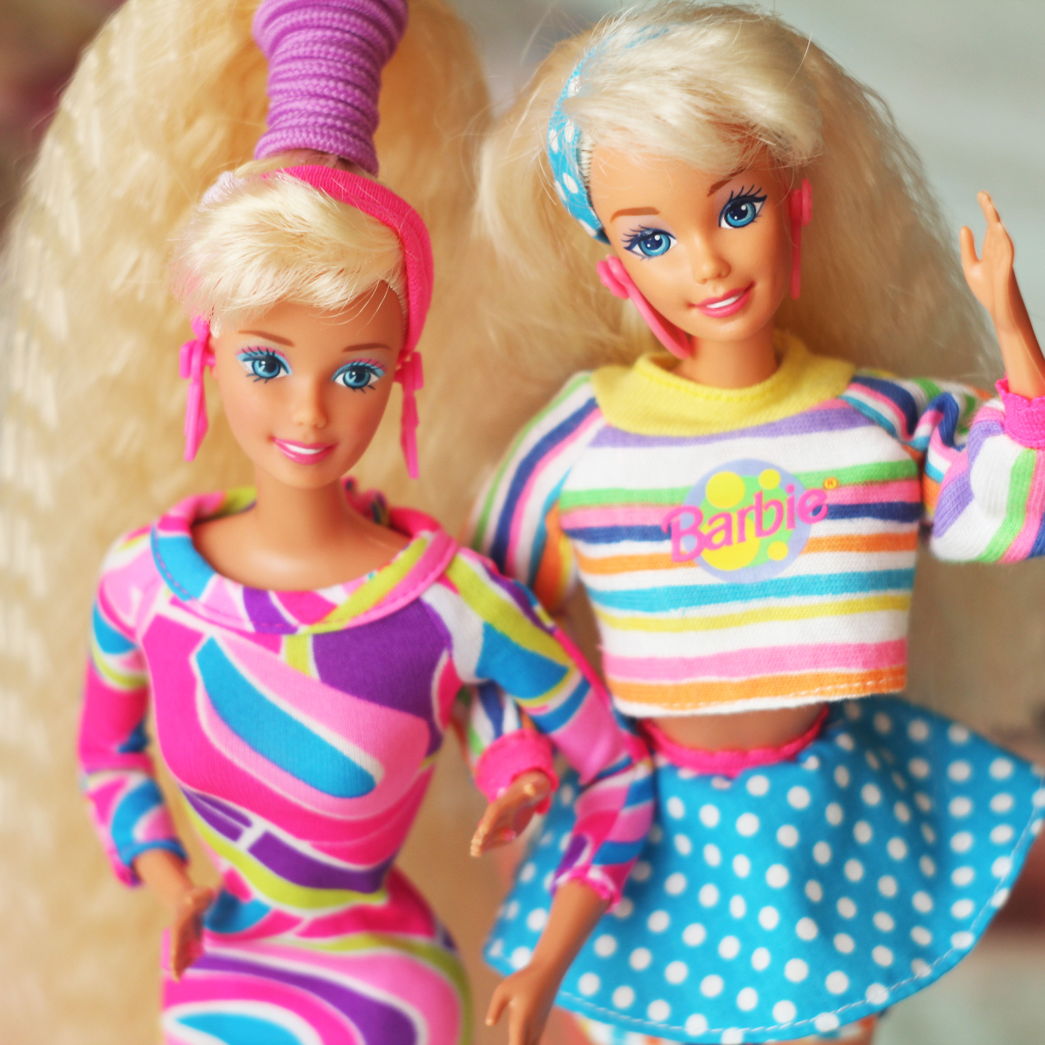 two Barbie dolls waving