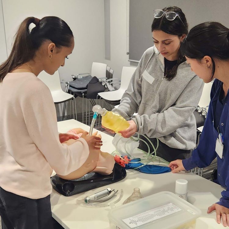 Students using medical equipment on manikin