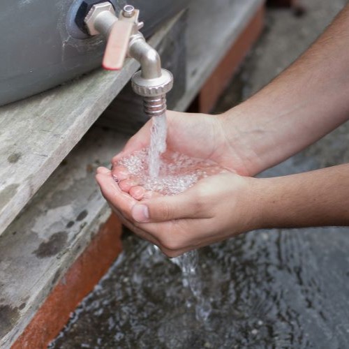 person collecting water from rainwater tank