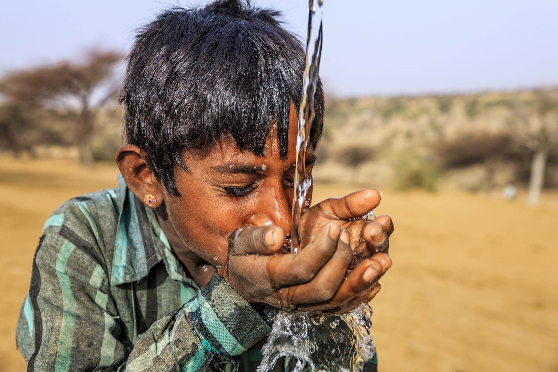 Photo of a young boy drinking water in the deserts of Rajasthan