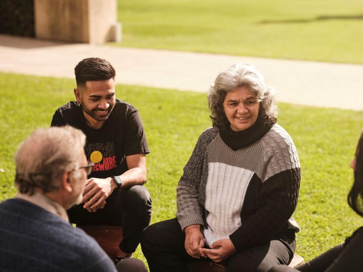 Group of people sitting on grass while conversing