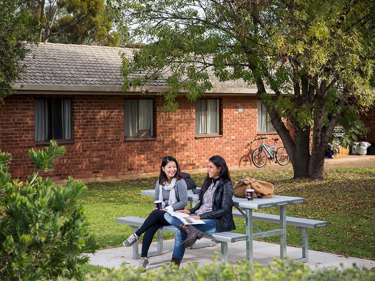 Two students sitting outside red-brick student accomodation