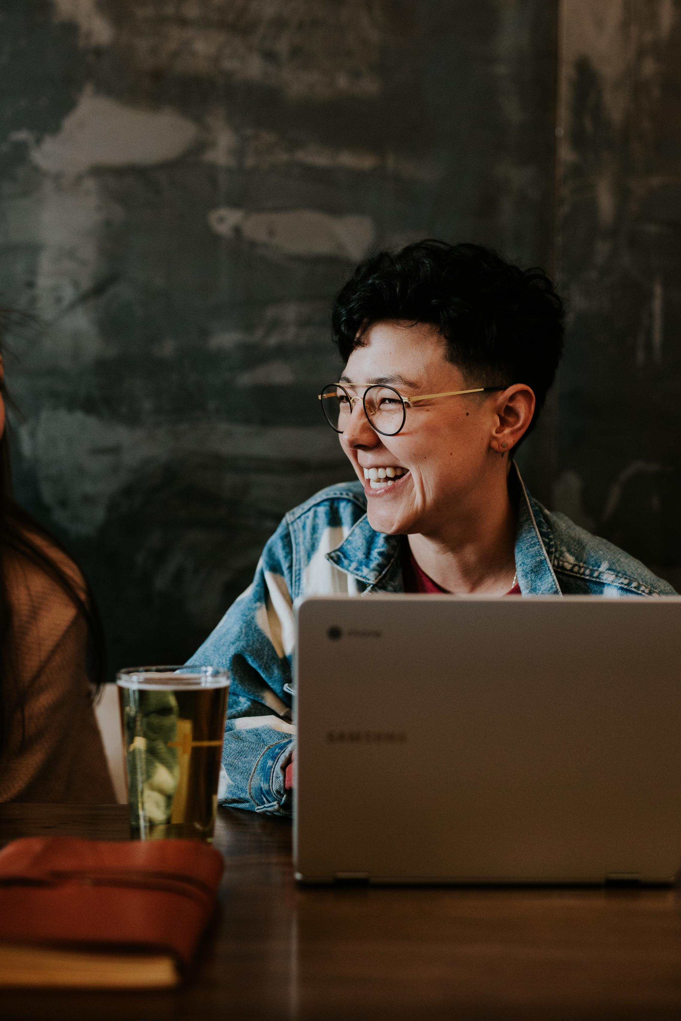 A person in front of a laptop, laughing 