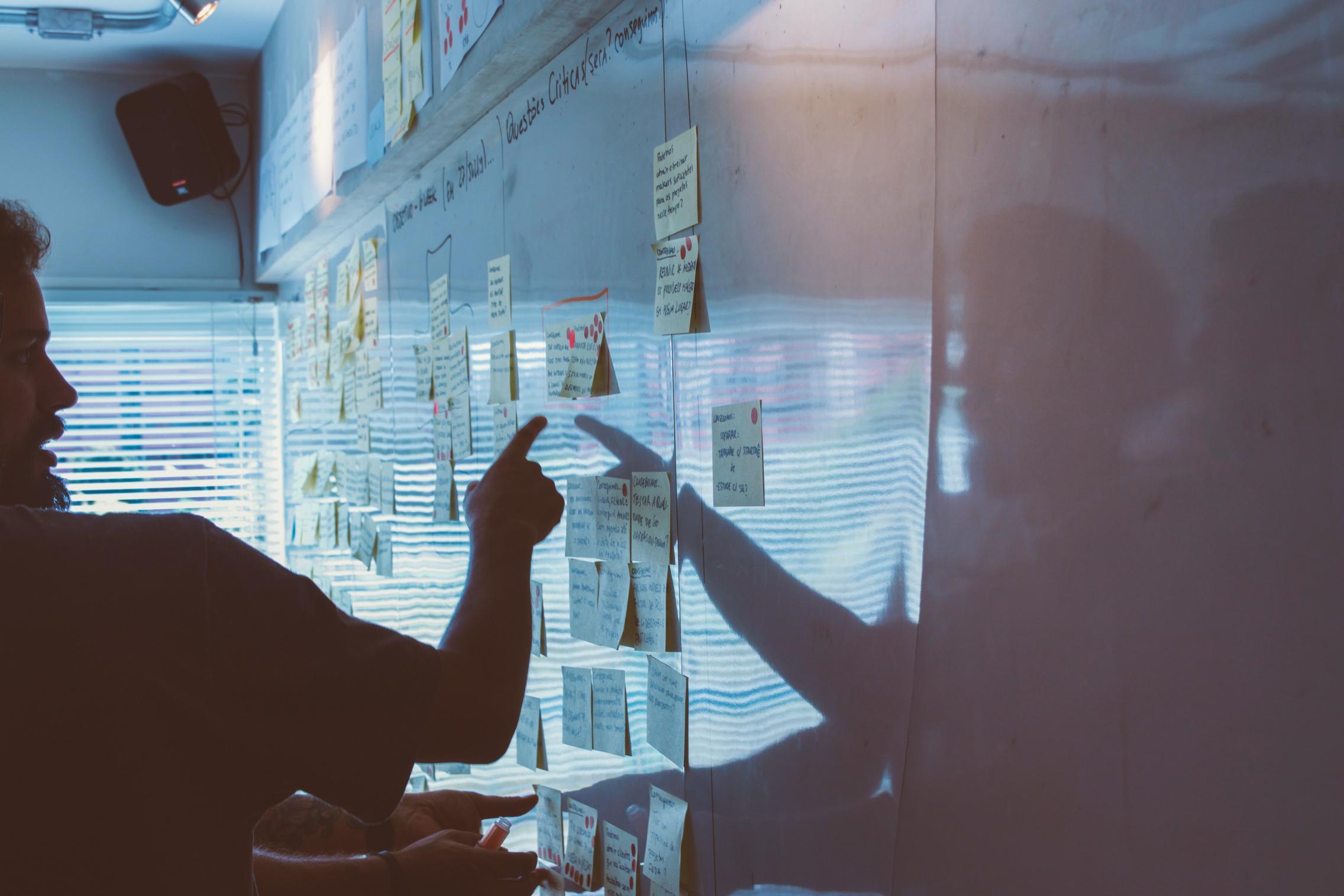 Post-it notes on a whiteboard and a man showing at them