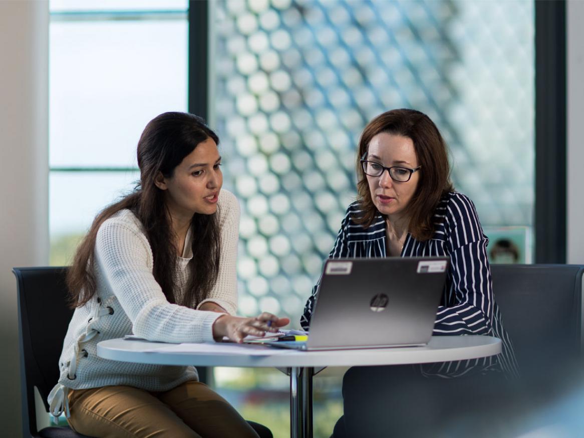 Two people working together using a laptop and looking very, very serious.