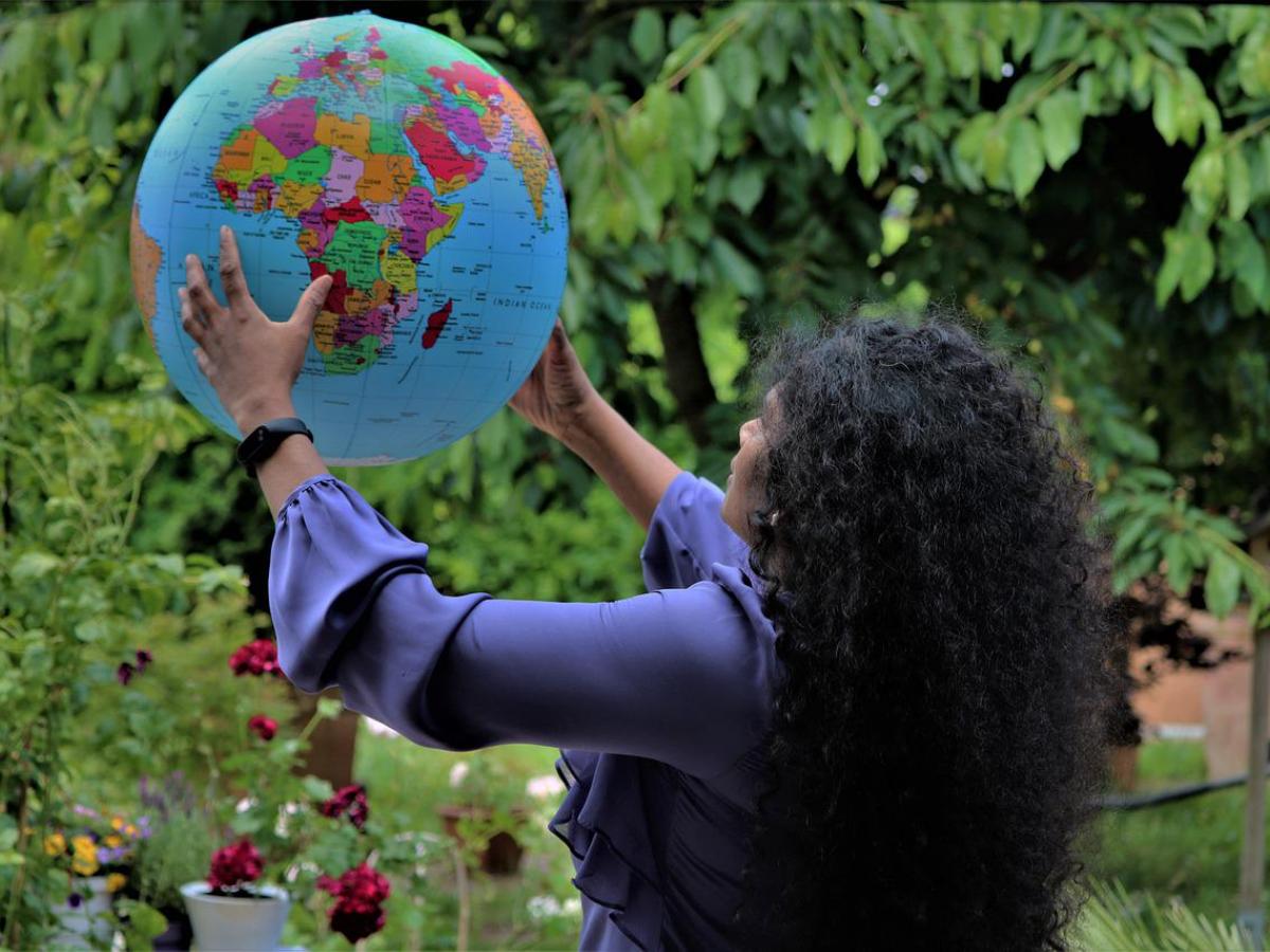 A woman holds up a world globe.