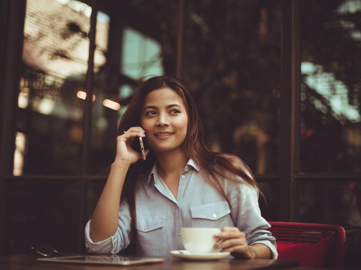 Woman drinking coffee while on the phone