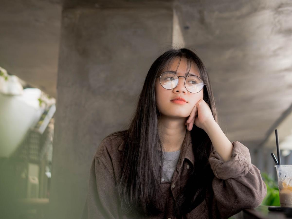 Young woman sitting pensively with her head resting on her hand