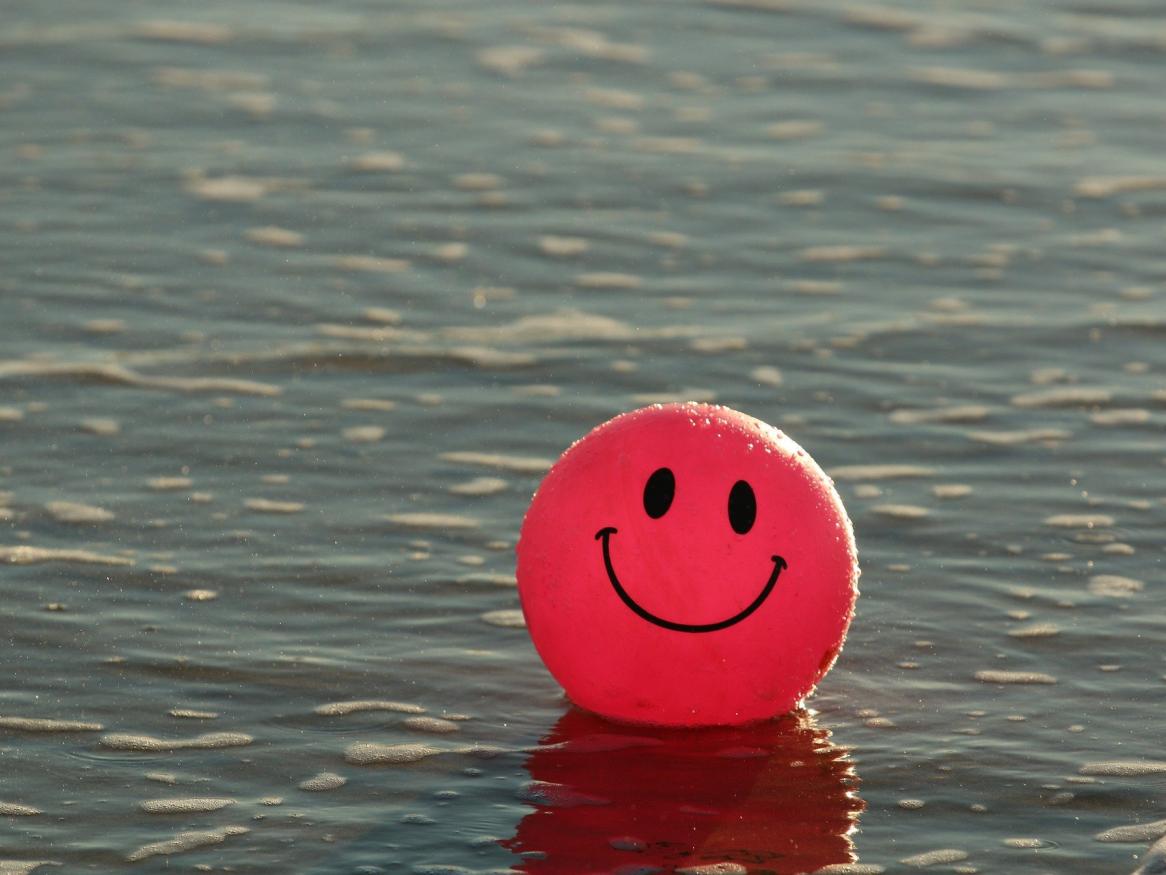 A ball with a smiley face on it floats optimistically in water.