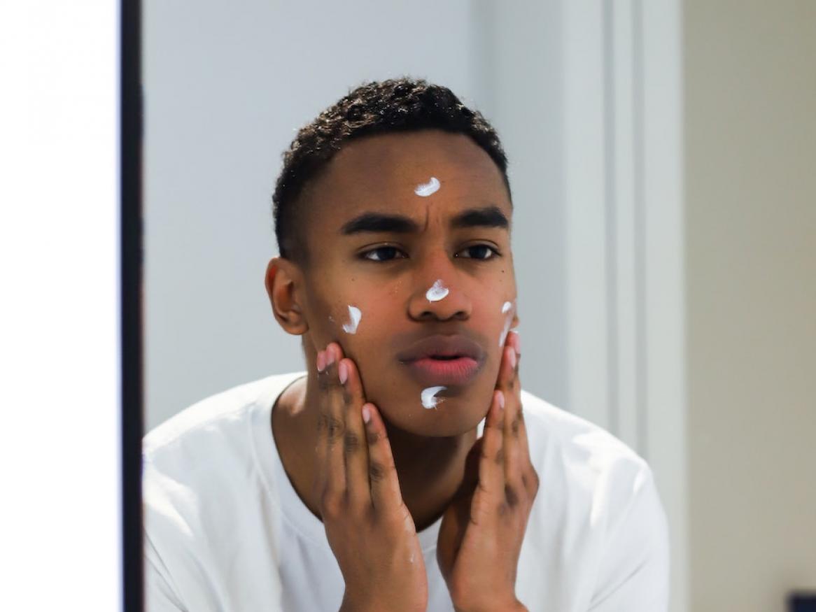 Man putting on face cream in front of mirror