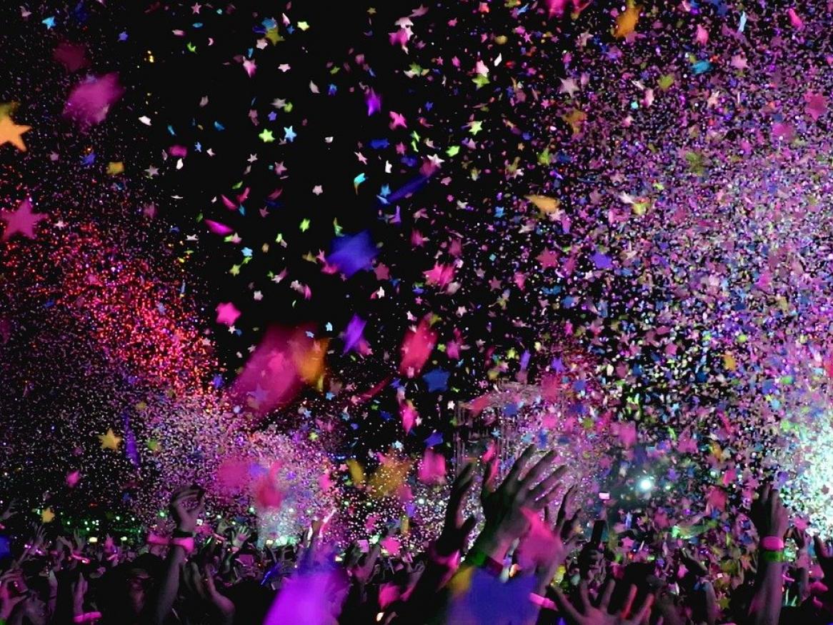 Festival confetti in the air above a crowd of hands