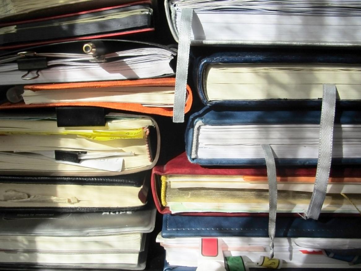 stack of 5 notebooks in 2 piles with page divider ribbons hanging down