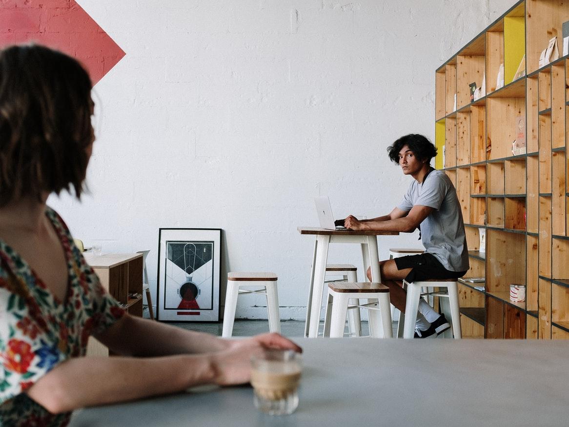 Two people at a cafe staring at each other from different tables