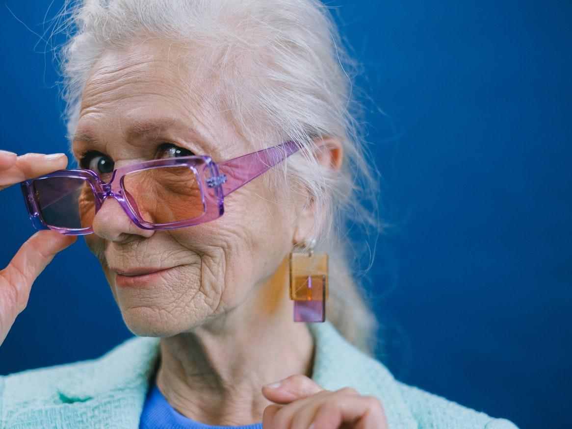 Senior women wearing purple glasses with orange and purple earrings