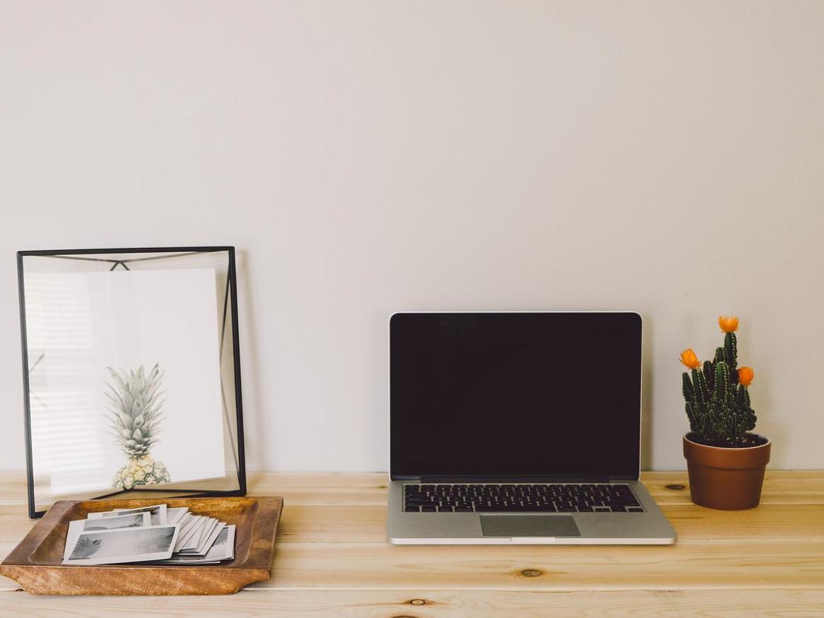 A laptop and other desk decor sits on a wooden desktop.