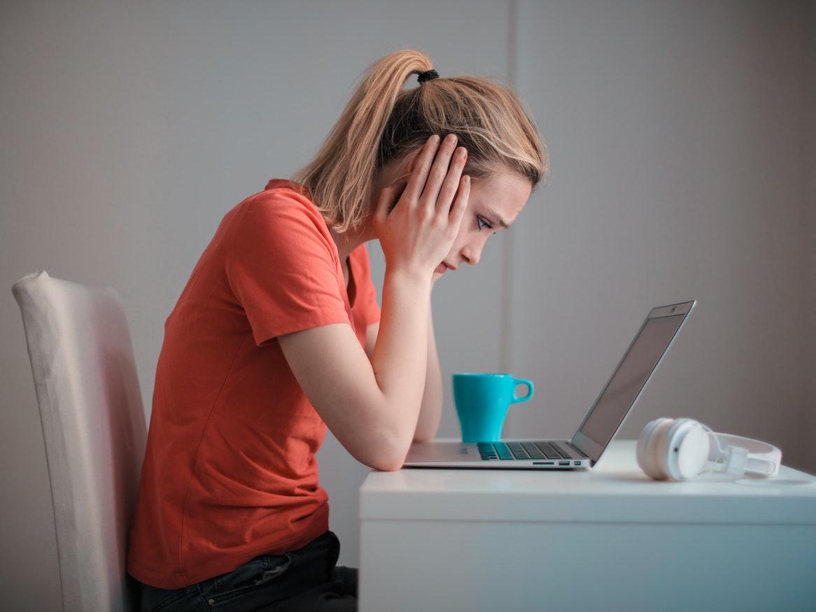 Girl with head in her hands looking at laptop screen