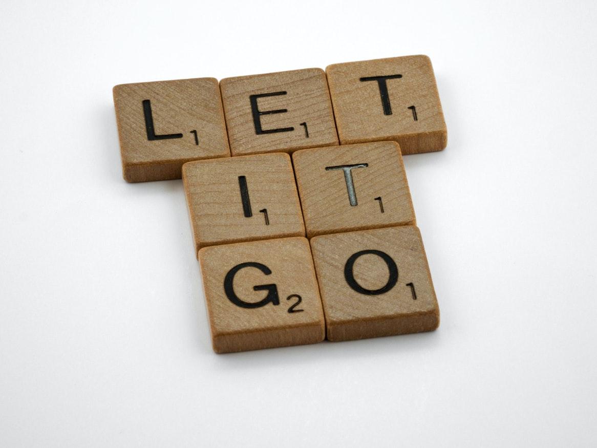 A white background with wooden scrabble letters spelling "let it go"