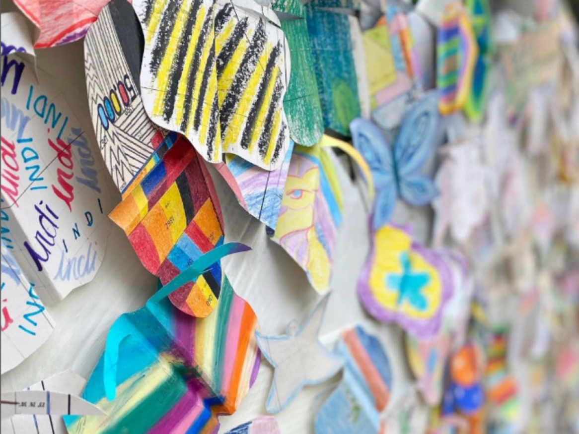 Colourful butterflies made from paper and stuck to a wall in close up