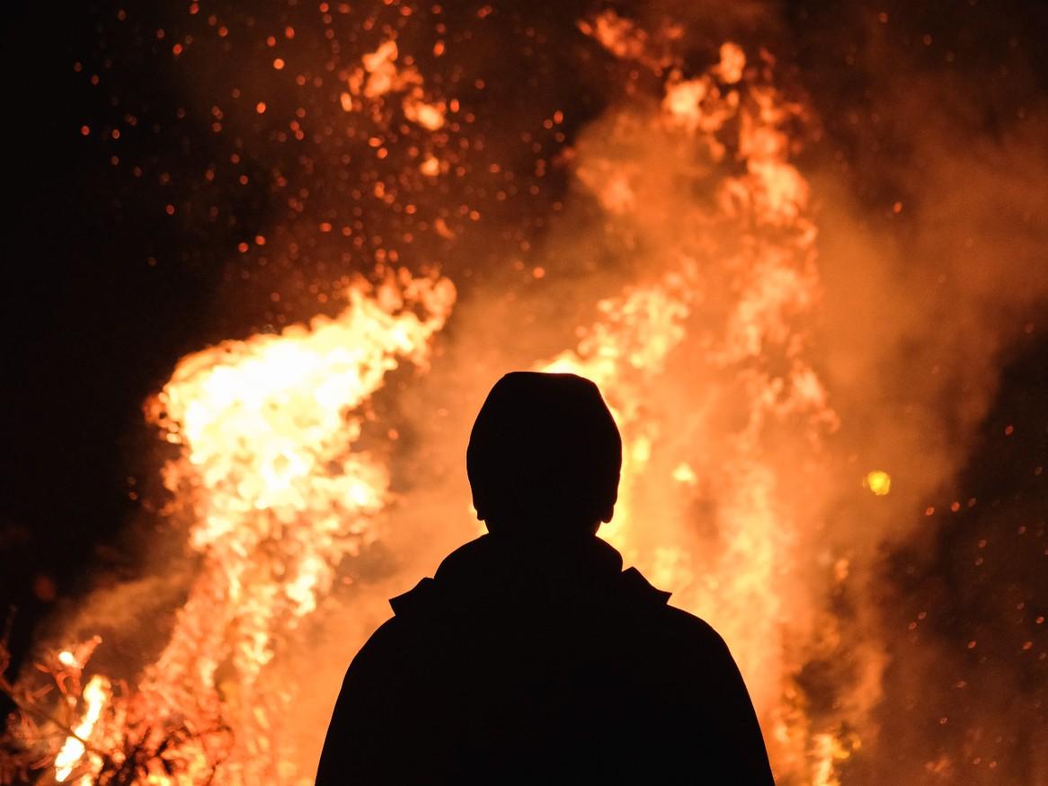 Silhouette of person watching a huge bonfire in front of them