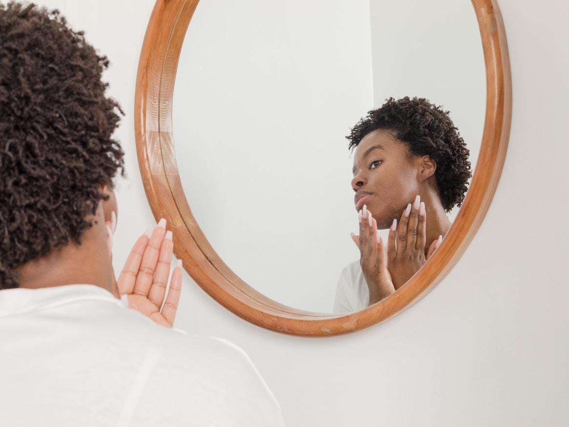 Woman applying skincare product on her face.