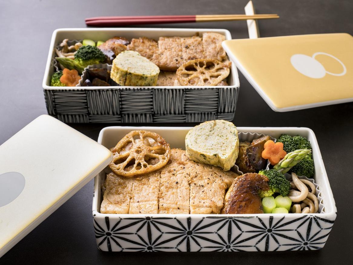Two open bento boxes, with chicken and vegetables inside.