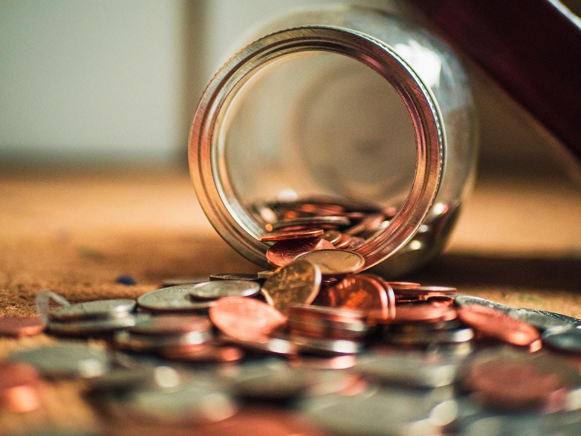 Coins spilling out of a glass jar. 